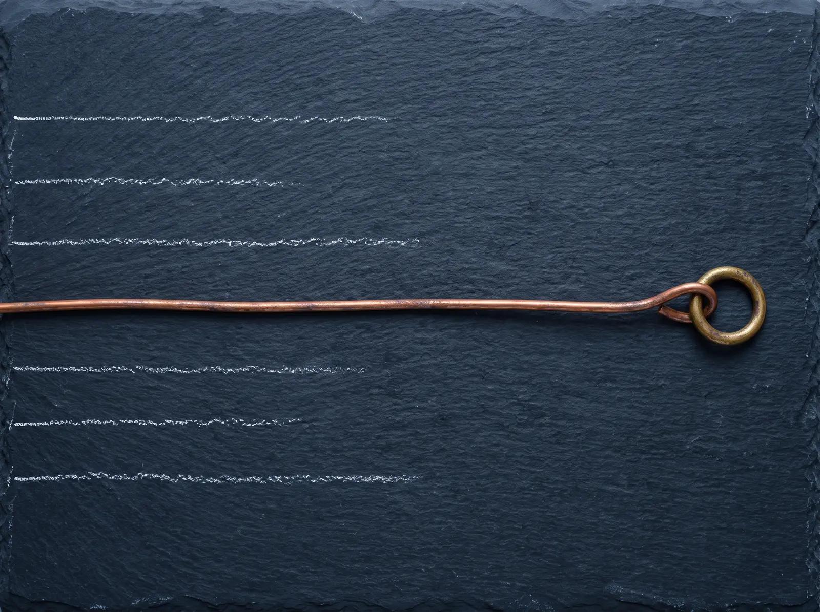 Still life of faded chalk lines stopping partway across dark blue slate and one continuous copper wire reaching a brass ring